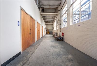 Industrial corridor with concrete floors, wooden doors, and large windows.