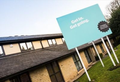 Large teal branded signage on the exterior of a brick office building.