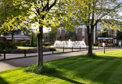 Lush green courtyard featuring a large decorative water fountain and mature trees.