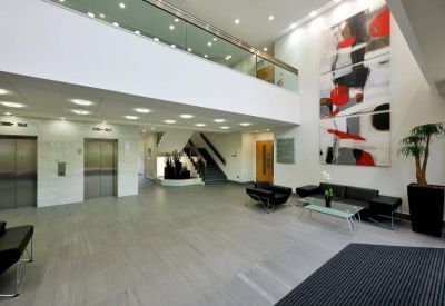 Bright double-height reception lobby with modern seating and large abstract wall art.