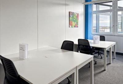 Luminous coworking space featuring white desks and a vibrant piece of abstract wall art.