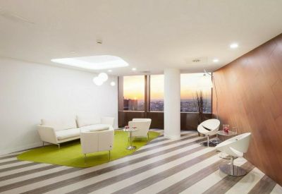 Modern reception lounge with green rug and white furniture.