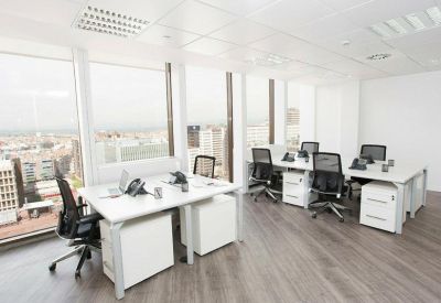 Spacious open-plan workspace with white desks and city views.