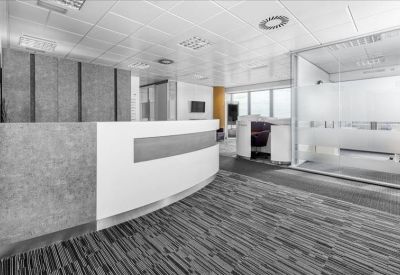 Sleek minimalist reception area featuring a curved white desk and wood accents.