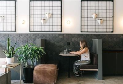 Private workstation booth set against a textured feature wall with indoor plants.