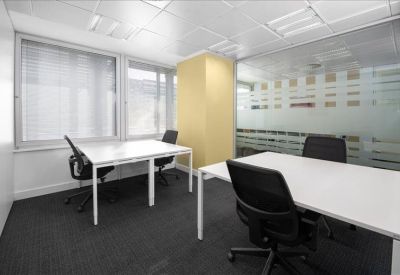 Bright private office suite with two white desks and a frosted glass wall.