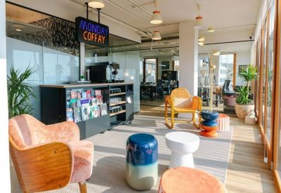 Stylish lounge area with colorful velvet armchairs, potted plants, and a coffee station.