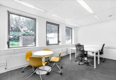 Collaborative office space with a round yellow table and separate workstations.