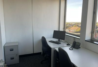 Dual-desk workspace with computers, office chairs, and views of the surrounding town.