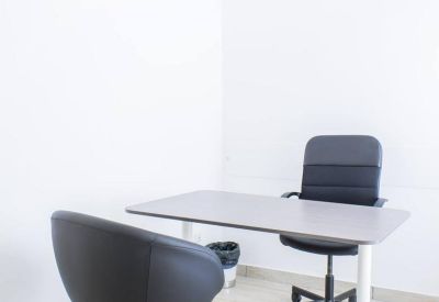 Compact two-person meeting space with grey desk and ergonomic black chairs.