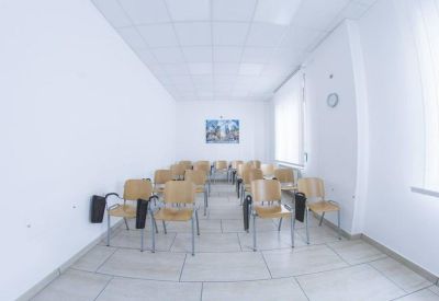 Spacious light-filled training room with rows of wooden chairs and white walls.