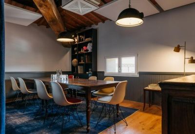 Sophisticated meeting room with a dark wood table, Eames-style chairs, and a blue patterned rug.