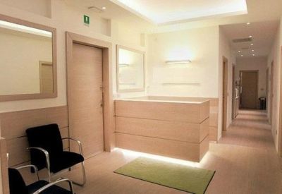 Bright reception area with a minimalist wooden desk and comfortable black guest seating.