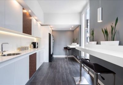 Sleek communal kitchen and breakout area with white counters and dark wood accents.