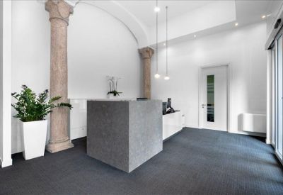 Elegant reception area featuring historic stone columns and a minimalist grey front desk.