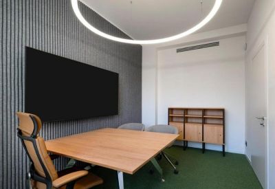 Close-up of a wood grain table top against a grey textured acoustic wall panel.