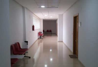 Bright, clean corridor with white walls and red seating areas.