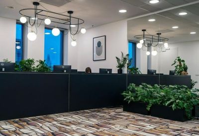 Modern office reception desk with low-hanging globe lighting and indoor plants.