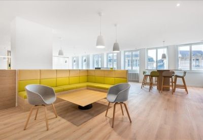 Lounge area with a yellow corner banquet, wooden floors, and stylish pendant lighting.