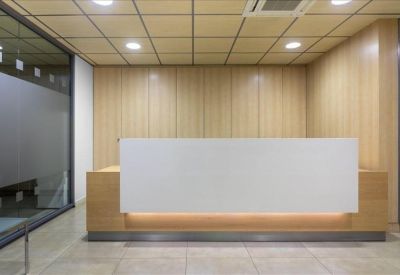 Minimalist reception desk with light wood paneling and warm under-counter lighting.