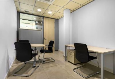 Private office suite with a round meeting table and a separate workstation.