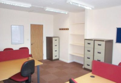 Office suite featuring desks with red partitions and white storage shelving.