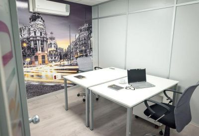 Compact two-person office featuring a vibrant city mural and laptops.