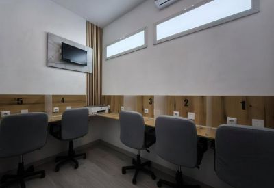 Coworking space with multiple grey chairs at a shared wooden desk.