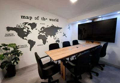 Spacious meeting room with a large wooden table and world map wall mural.
