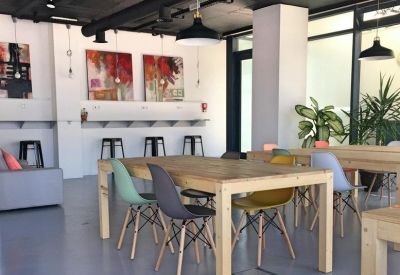 Bright coworking area with wooden tables, colourful chairs, and modern pendant lighting.