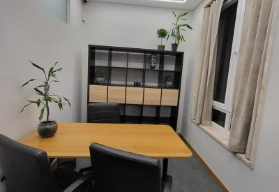 Meeting room with a rectangular wooden table, black office chairs, and modern shelving unit.