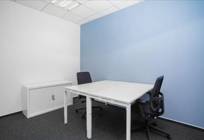 Modern coworking area with white desk, colorful chairs, and wooden shelving.