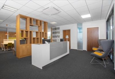 Reception area featuring a white front desk and stylish grey armchairs.