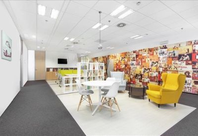Communal lounge with a colorful mural wall and a bright yellow wingback chair.