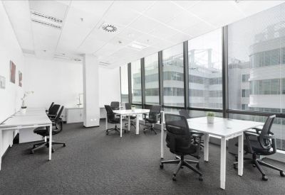Modern open-plan office with white desks and large floor-to-ceiling windows.