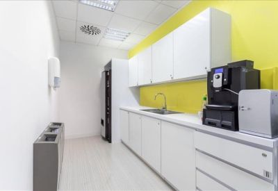 Modern office kitchen and coffee station with vibrant yellow walls.