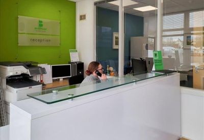Modern reception desk with a glass top and a green feature wall.