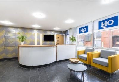 Bright reception area with curved white desk and yellow lounge chairs.