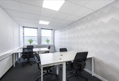 Bright multi-desk office with grey patterned feature wall and natural light.