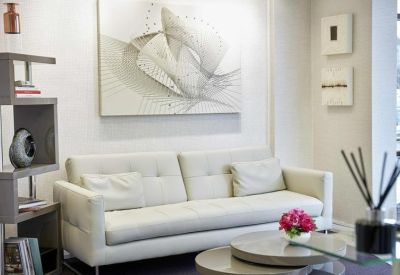 Lounge area with a white leather sofa and abstract wall art above it.