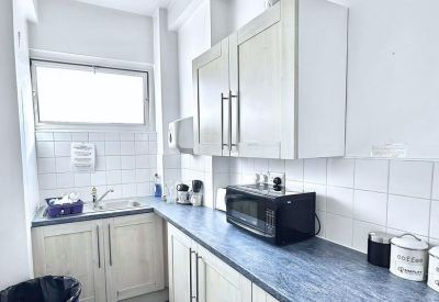 Clean communal kitchen area with light wood cabinets and blue countertops.
