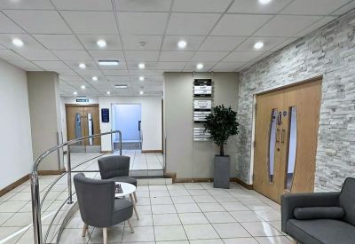 Bright modern reception area with grey armchairs and stone feature wall.