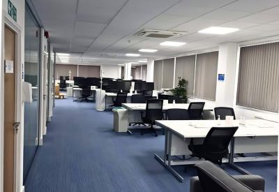 Spacious open-plan office with numerous desks, computers, and blue flooring.