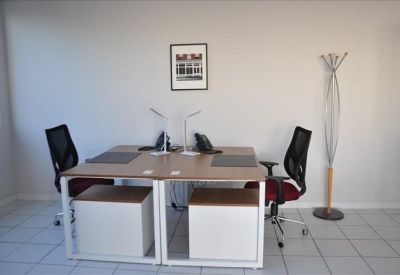 Private office workspace with two wooden desks, black mesh chairs, and white storage cabinets.
