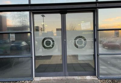 Modern glass entrance with branded decals and automatic doors.