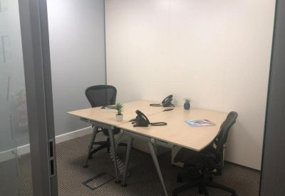 Two-person private office with light wood desks and ergonomic chairs.