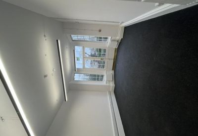 Compact office space with wide windows and black carpeting.