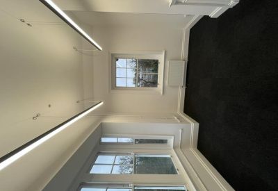 Narrow office room with large window and overhead lights.