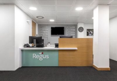 Professional reception area with a wood-panelled desk, Regus branding, and clean white pillars.