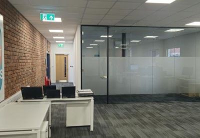 Office entrance with a branded brick wall and glass partitions.